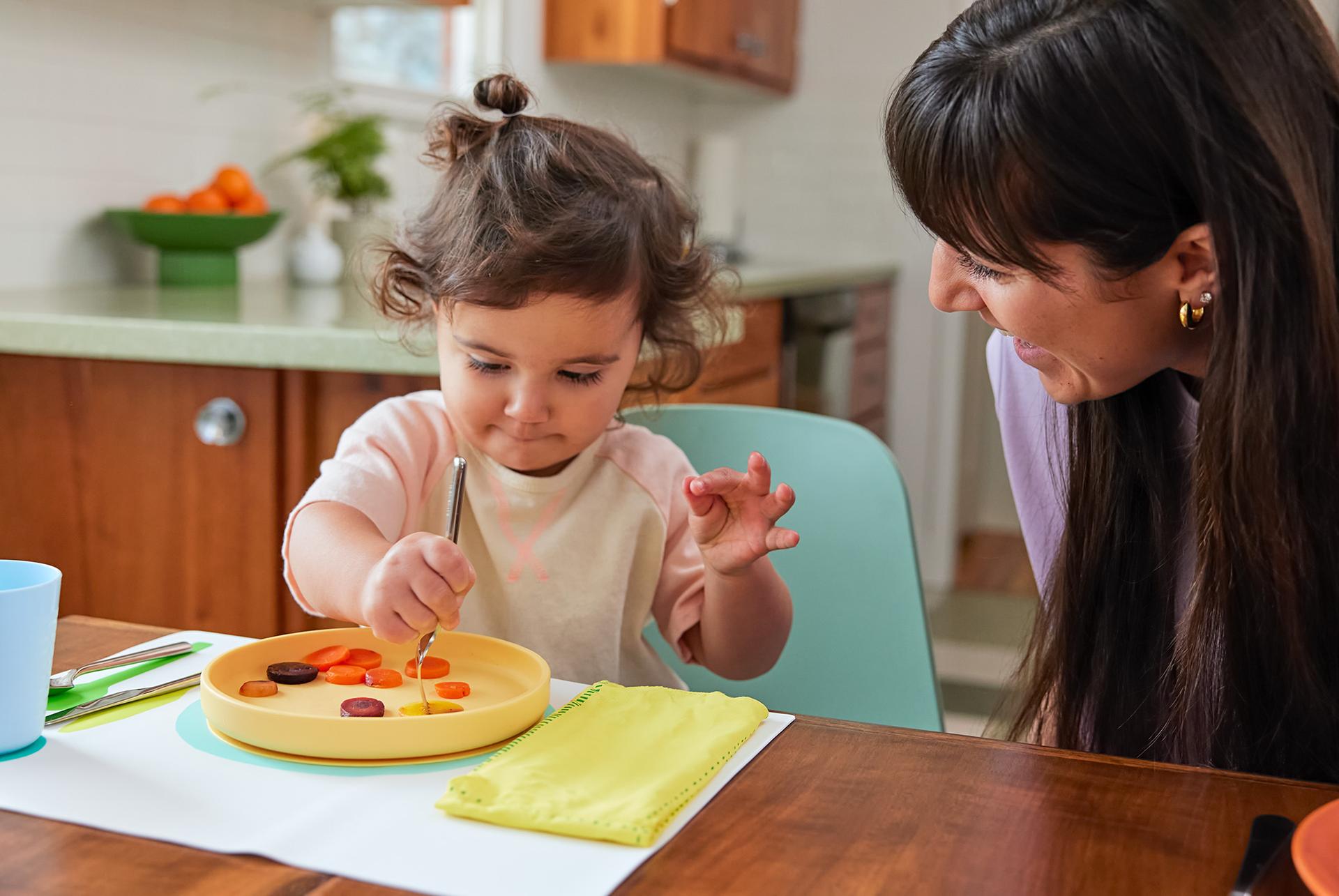 Child using the Montessori Placemat & Utensils by Lovevery